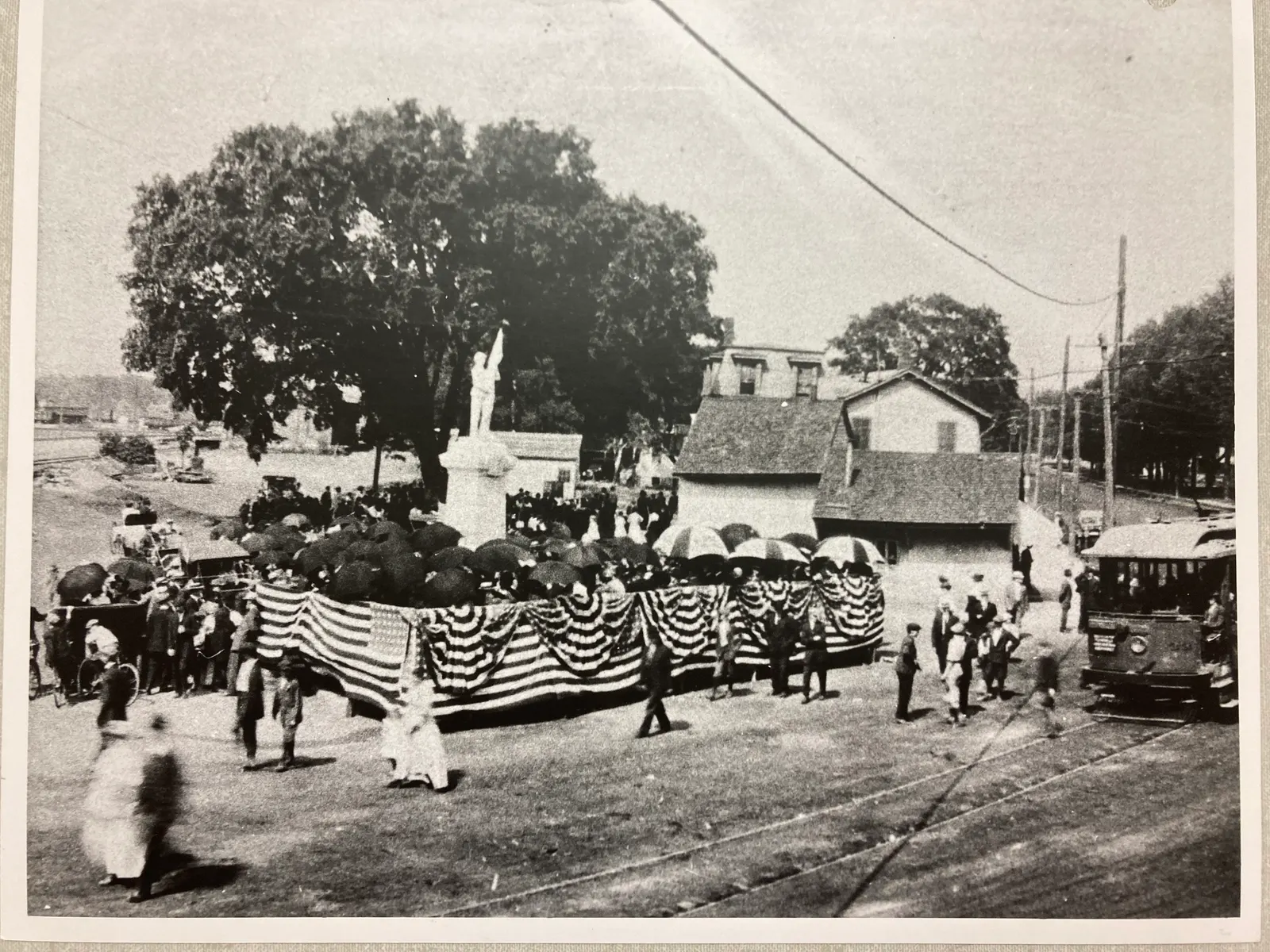 Plainville townspeople gathered around a monument with American flags